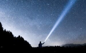 Man shining a flashlight into a starry sky.